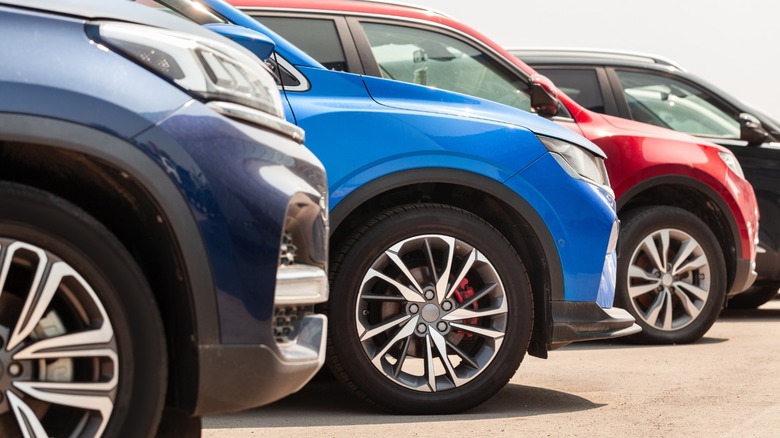 Close-up of blue, red, silver and dark-gray SUVs parked side by side in a dealership lot