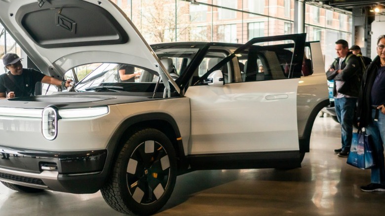 People looking at a new Rivian R2 at a showroom in New York City.