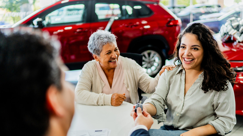 Two women receiving the key to the car they just bought