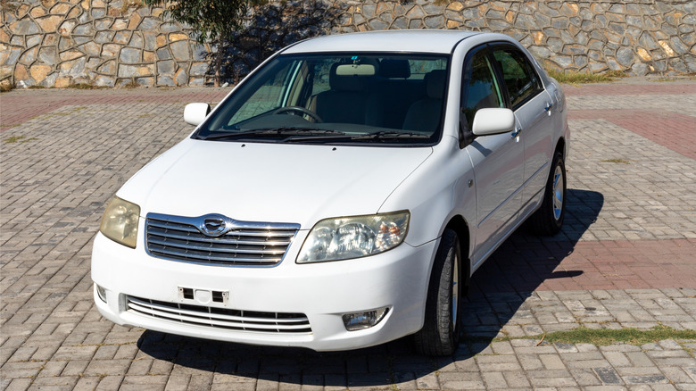White Toyota Corolla car parked on a brick driveway