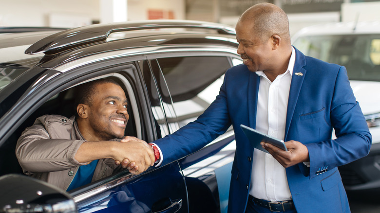 Car salesman shaking hands with a new customer