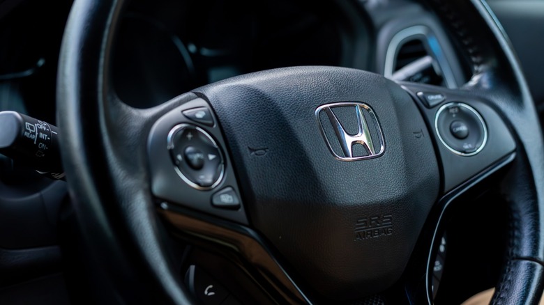 Close-up of a Honda steering wheel with the Honda emblem and integrated audio and cruise-control buttons