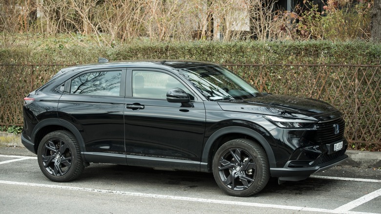 Black Honda HR-V parked outdoors beside a hedge and wooden fence