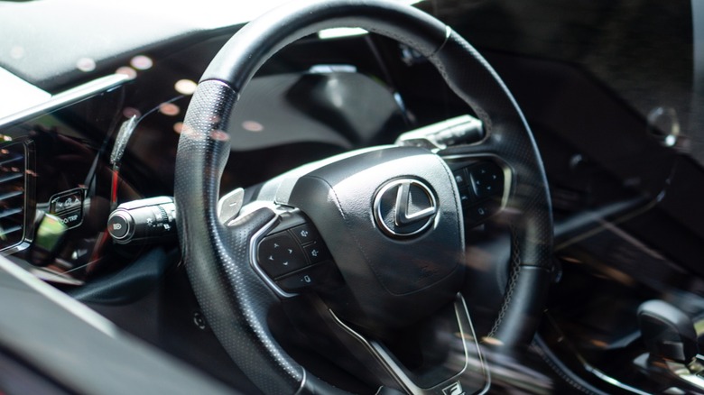 Close-up of a Lexus interior showing the leather-wrapped steering wheel with the Lexus emblem