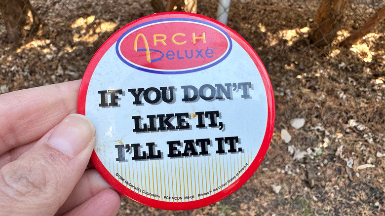 hand holding a promotional Arch Deluxe button