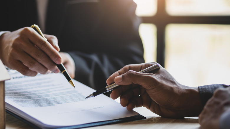 Hands signing paperwork