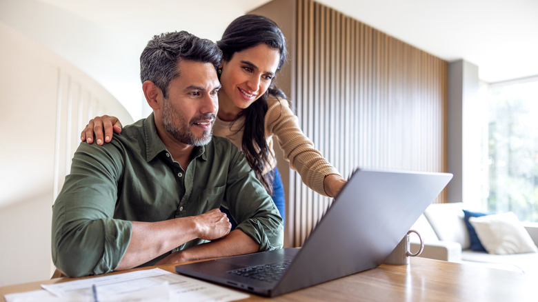 Couple smiling and looking at their laptop