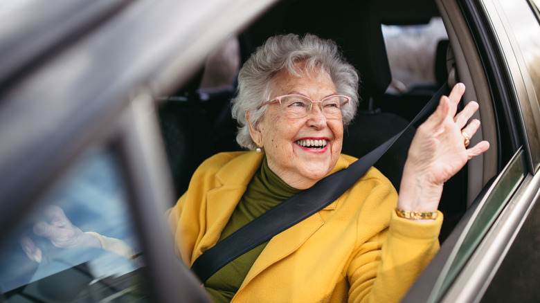 Older female driver with glasses in front seat of car