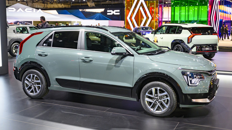 Gray-green Kia Niro Hybrid displayed at an indoor auto show