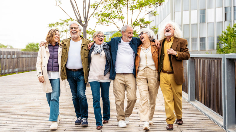 A laughing group of seniors walking on a boardwalk together