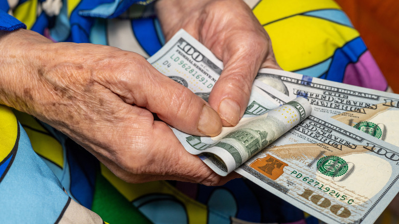 An elderly woman holding a wad of cash in her hands