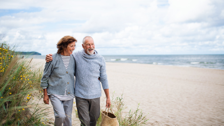 Senior man and woman walking along beach