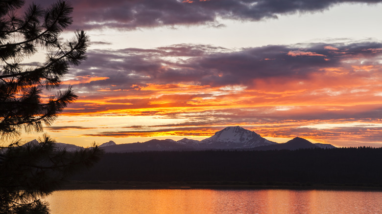 A sunset over a lake with mountains in the background