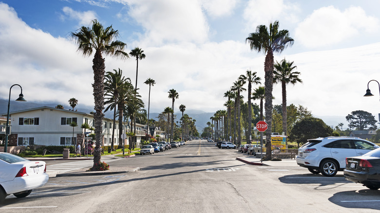 Street in Carpinteria, CA with palm trees, cars, and clouds