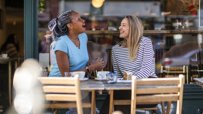 Two Gen X women enjoying a conversation on a cafe patio.