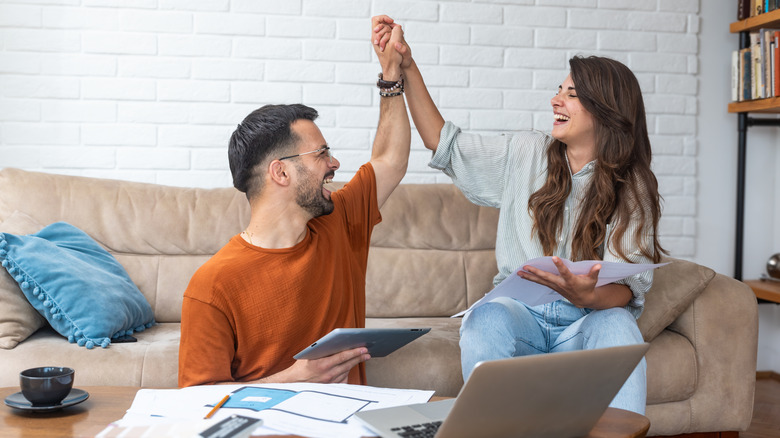 Young couple looks at papers/computer and high fives