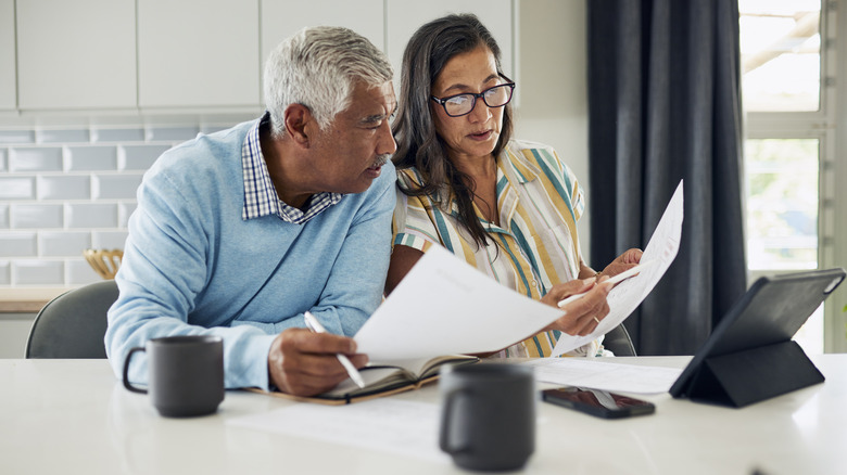 A senior couple budgets in their kitchen