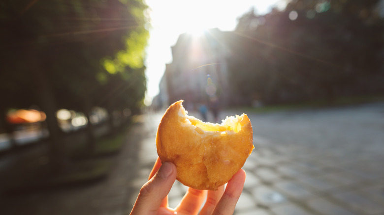 Hand holding a street food item with a bite taken out