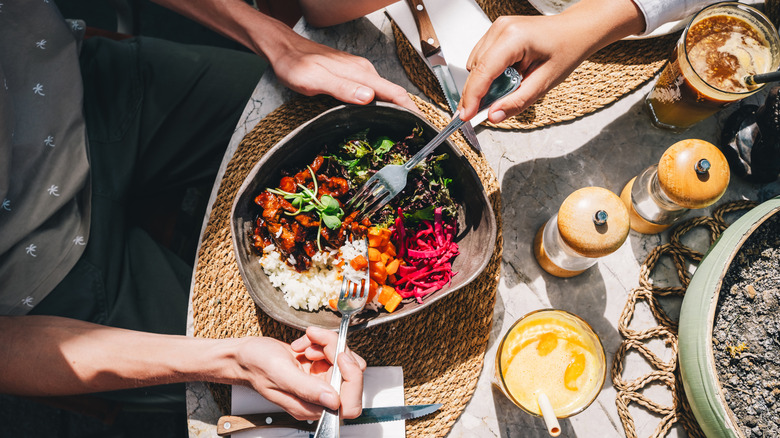 Waitress serve the table with bowl with healthy food in sunny day