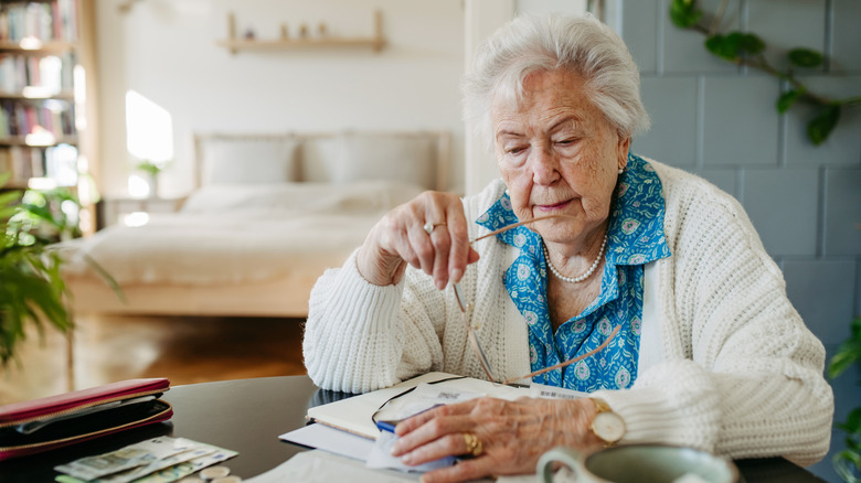 Senior woman has financial problems. Counting money, monthly pension, don't have enough money for paying bills.
