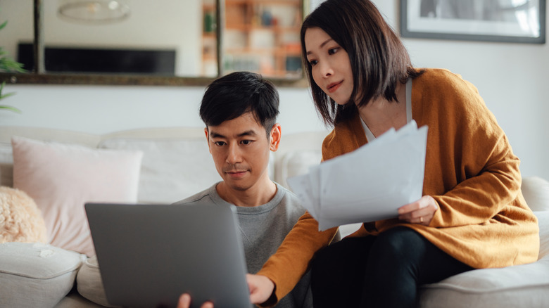Couple manages budget using computer.