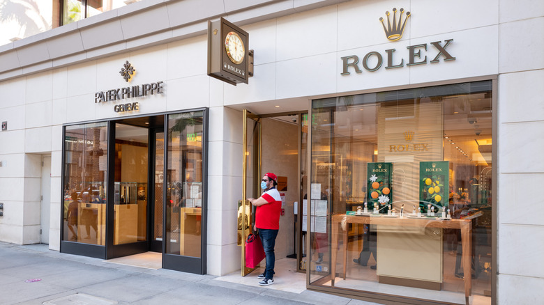 Male customer leaving a rolex store with shopping bags and a mask