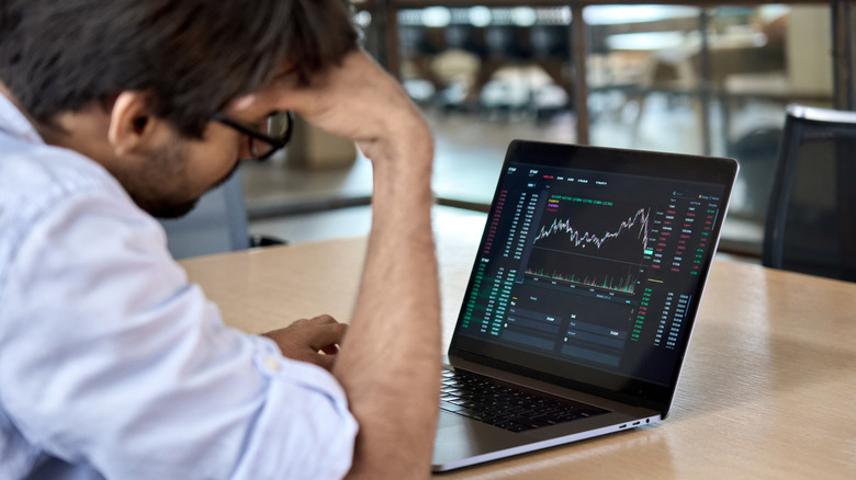 Stressed out man checking stocks on his laptop