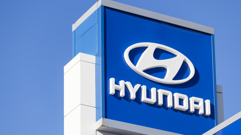 yundai sign and logo above car dealership lot over building and showroom with clear, blue sky in background.