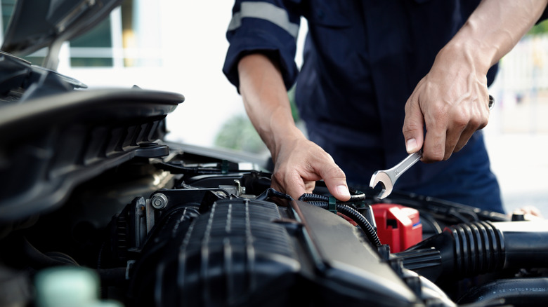 Mechanic holding wrench and working on a car engine