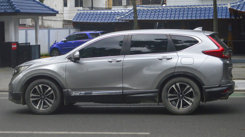 A gray Honda CR-V driving on the road in a city.