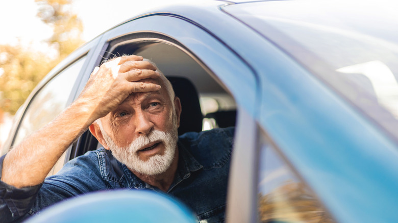Flabbergasted old man sticks head out of driver's side window of car