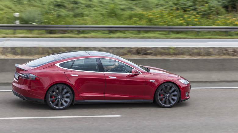 A red Tesla Model S driving on a highway