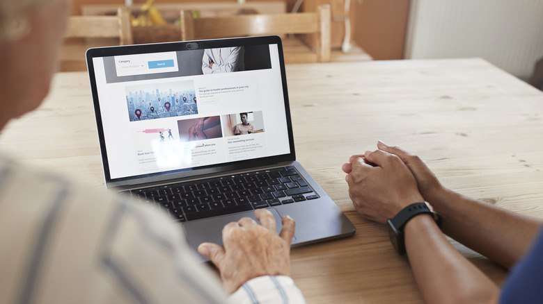 Cropped image of senior woman using a laptop.