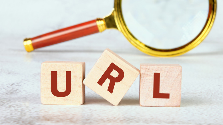 Animated letters spelling URL sit on a clean surface, with a magnifying glass in the background.