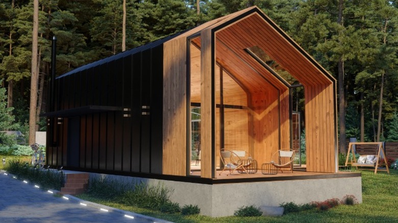 A luxurious tiny home with a vaulted roof and wood siding sitting on a concrete foundation.