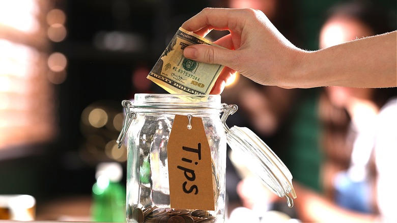 person adding to tip jar