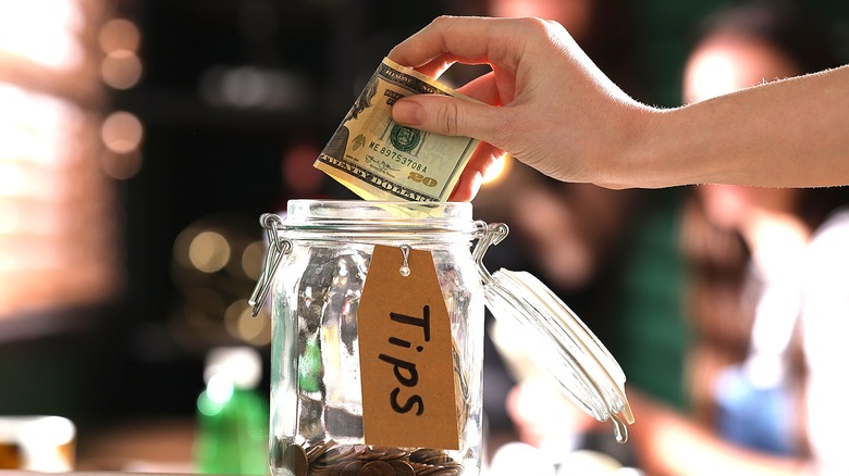 person adding to tip jar