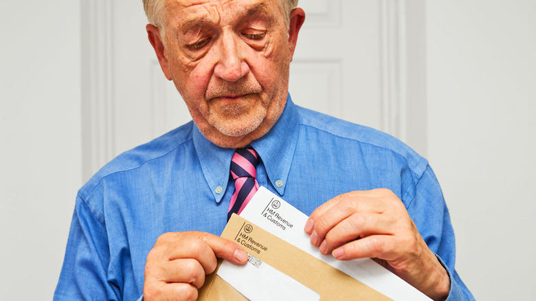 A man pulling out an envelope from a stack and on it says "HM Revenue & Customs"