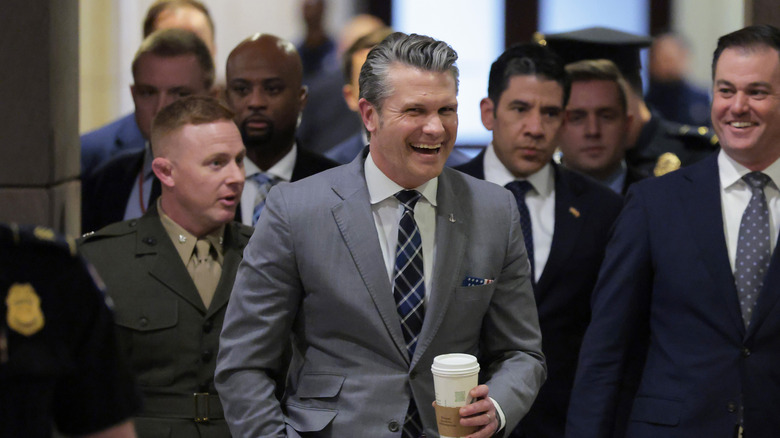 Secretary of Defense Pete Hegseth arriving for a congressional hearing with a group of people behind him