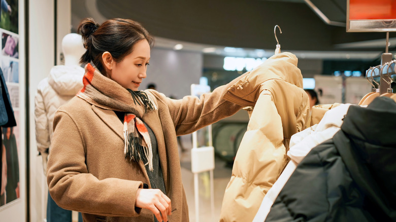 A young woman shopping for coats at the mall