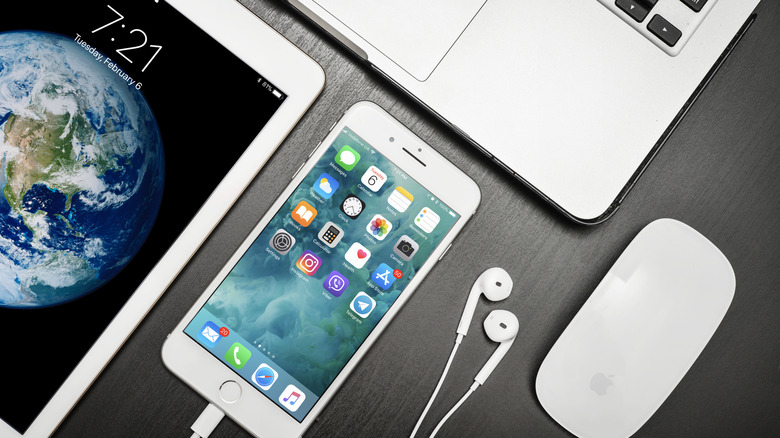 iPad, iPhone with earplugs, and Macbook