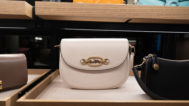 white Coach handbag with logo sitting on shelf