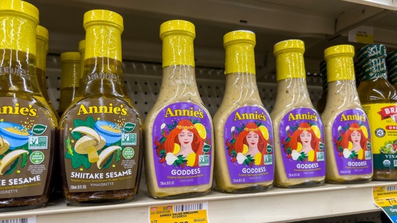 Full-sized bottles of Annie's Naturals salad dressing for sale on a store shelf at a higher price point than the smaller bottles at Dollar Tree.