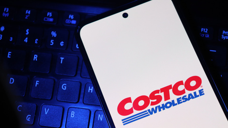 A smartphone screen displaying the Costco logo with a keyboard in the background.