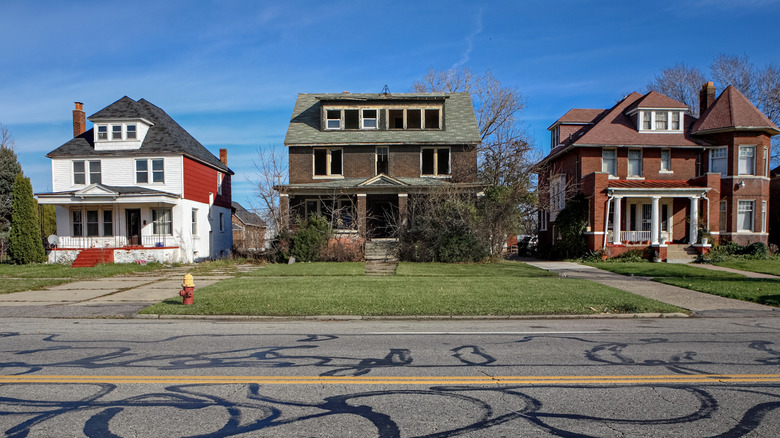 A vacant and dilapidated house between a pair of newly renovated homes in Detroit.
