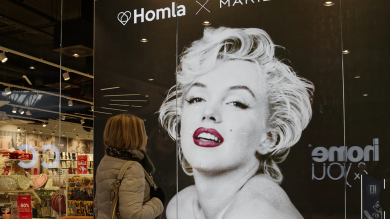 Person walking past a storefront featuring Marilyn Monroe's image
