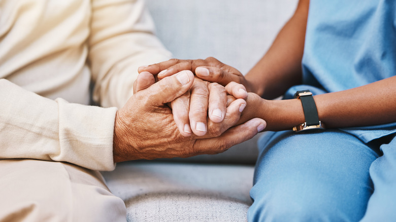 Close up of senior patient's hands grasping a younger medical professional