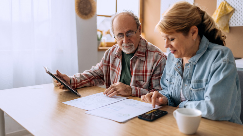 Seated mature couple look over papers laid flat on a table