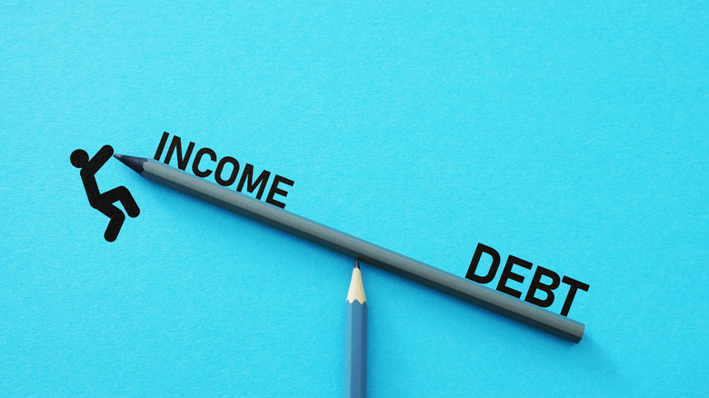 debt and income on a pencil see-saw