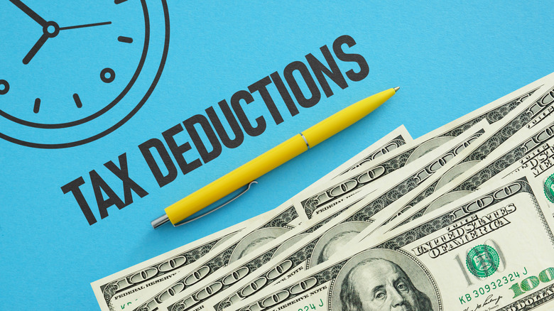 The words "tax deductions" spelled out next to a pen and stack of $100 bills